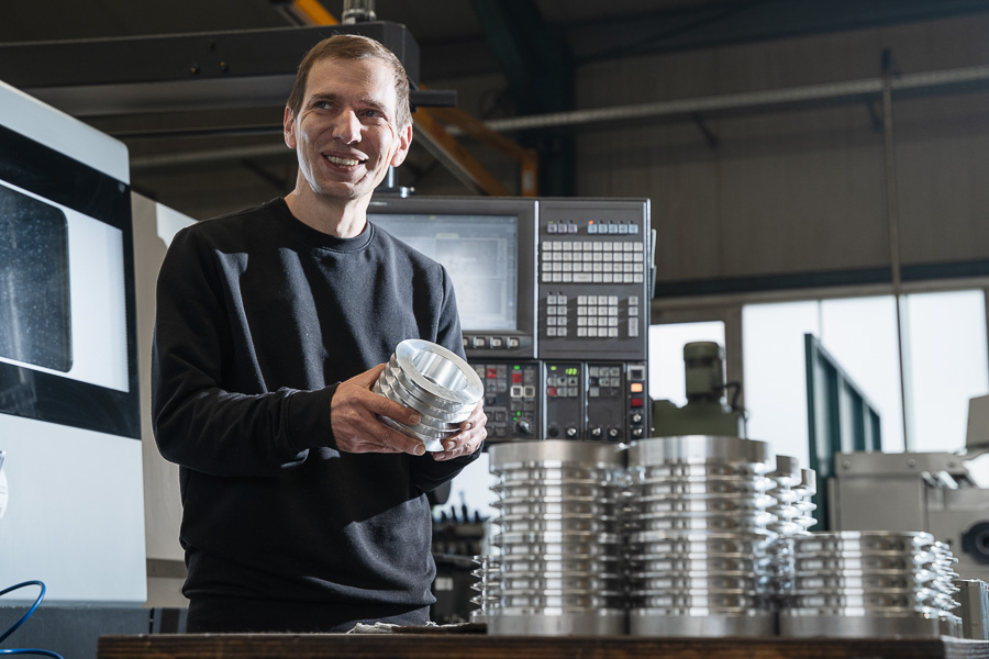 Mitarbeiter freundlich mit einem Werkstück aus Serienfertigung bei Neuhäusler Zerspanungstechnik. 